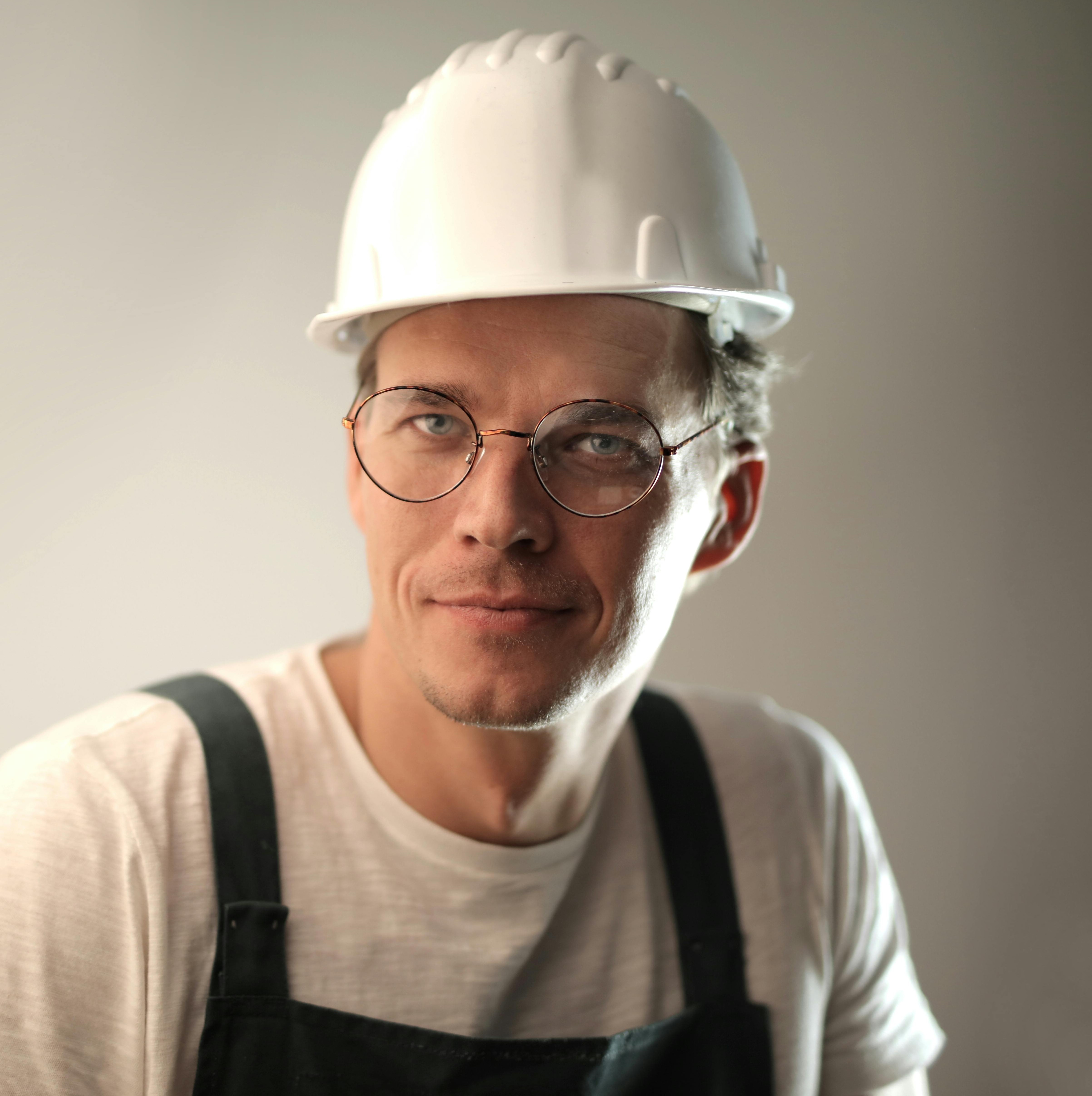 man with glasses on and a white hard hard, looking at the camera